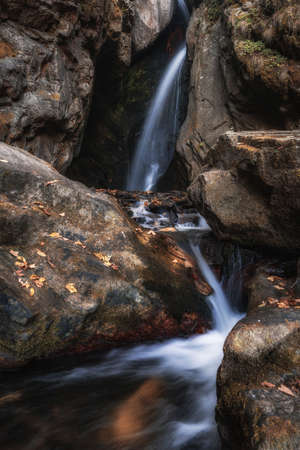A beautiful shot of the waterfall in the forest full of red and orange foliage
