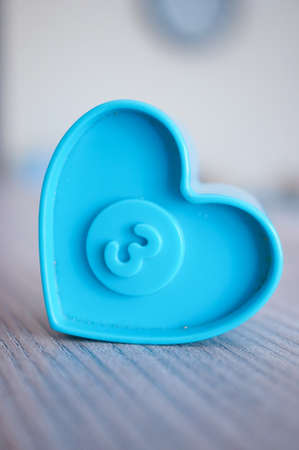 A closeup shot of a blue heart plastic toy with the number three on itの写真素材