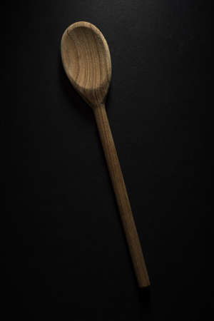 A vertical shot of a big wooden spoon isolated on black backgroundの写真素材