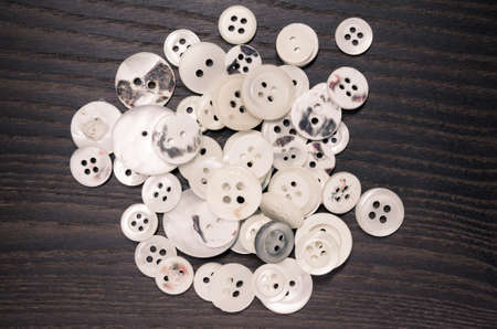 An overhead shot of old clothing buttons on a dark wooden backgroundの写真素材
