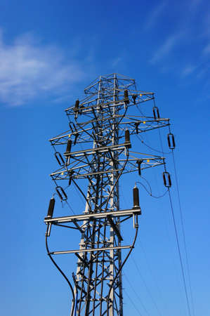 A low angle of a high voltage electric post against a blue sky on a sunny day