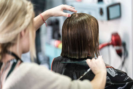 A vertical closeup shot of a hairdresser cutting a woman's short hair in a beauty salonの写真素材