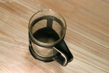 A high angle closeup shot of a glass coffee mug on a wooden tableの写真素材
