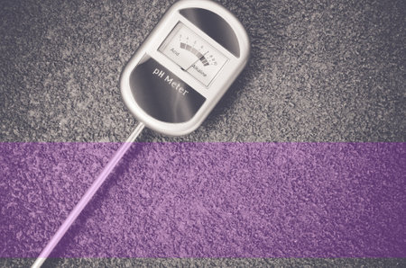 A top view closeup of an analog tool to measure soil ph on a rough textured backgroundの写真素材