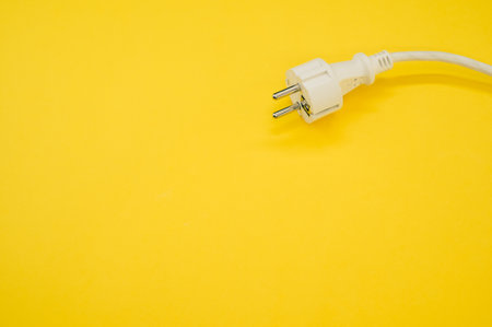 A high angle shot of an electrical wire and plug on a yellow surface