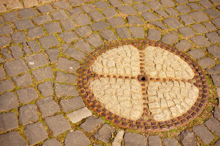 A manhole on a cobblestone in the street during daytimeの写真素材