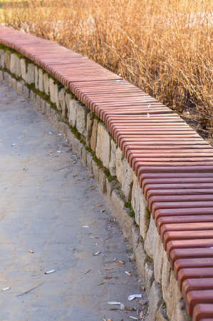 A vertical shot of a long wooden bench in the a parkの写真素材