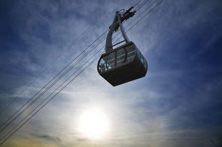 A low angle view of a cable car under the sunlight and a cloudy sky during the sunsetの写真素材