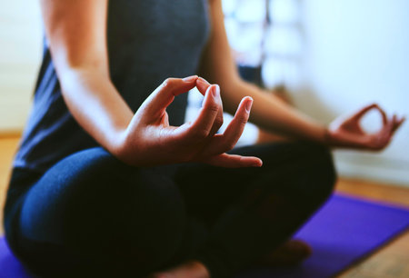 A young woman sitting on a blue rug in a meditating poseの写真素材