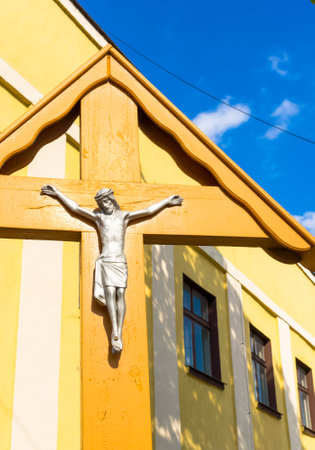 A vertical shot of a wooden cross and a yellow house on the backgroundのeditorial素材
