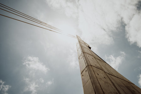 A low angle shot of a concrete column with cables against a bright cloudy skyの写真素材