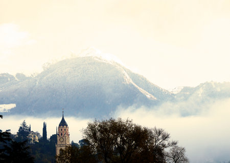 A beautiful shot of a tower with a high mountain in the background during daytimeの写真素材