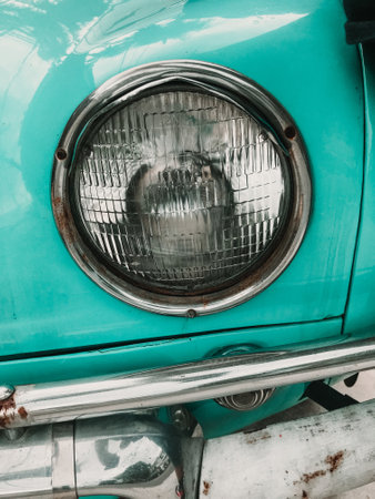 A vertical shot of a headlight on a teal colored vintage carの写真素材