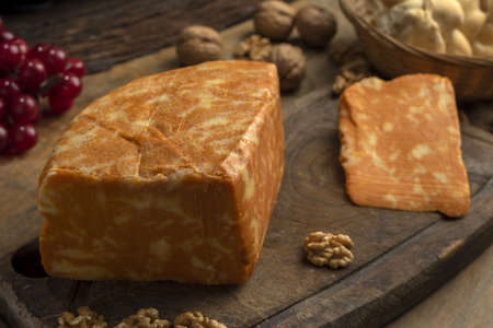 A closeup shot of a delicious block of marbled cheese on a wooden board