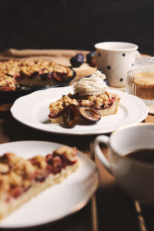 The delicious  Plum pie with coffee and ingredients with fabric on a wooden table with fabric backgroundの写真素材