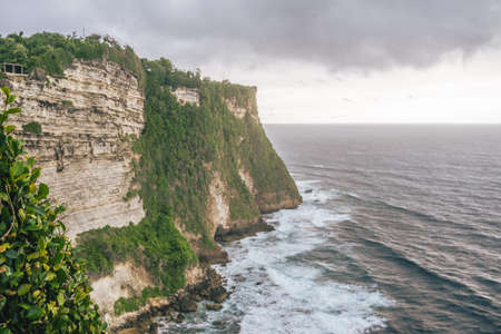 A long shot of Uluwatu cliffs in Bali, Indonesia under cloudy skiesの写真素材