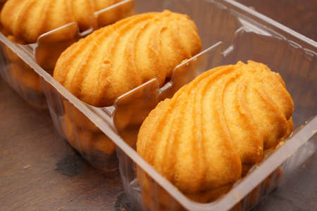 A close up shot of sweet cookies on a plastic box on a wooden table