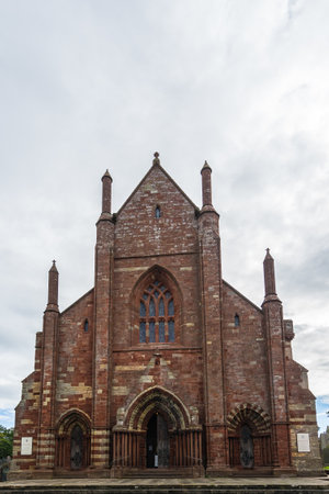 A vertical shot of St Magnus Cathedral in Kirkwall Scotland with a cloudy gray sky in the backgroundの写真素材