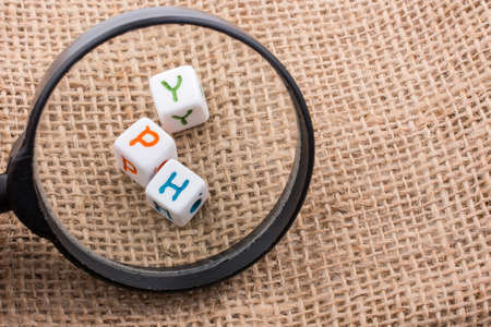 A closeup shot of letter toy blocks on a brown woven surface under a magnifying glassの写真素材