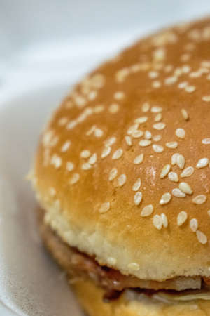A vertical closeup shot of a cheeseburger in a white plateの写真素材