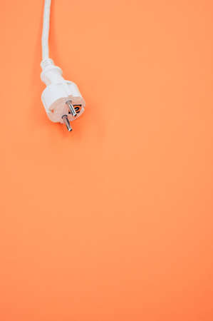 A vertical shot of an electrical wire and plug on an orange surfaceの写真素材