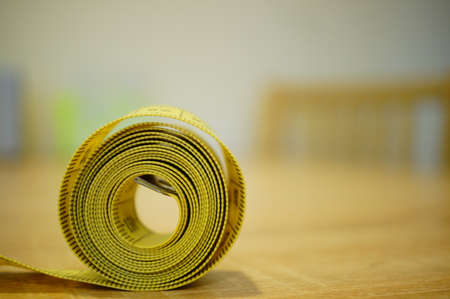 A closeup shot of a yellow measuring tape on a blurred background