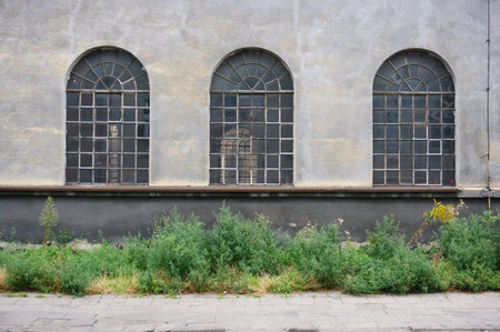 A panoramic shot of arched glass windows on a concrete wall