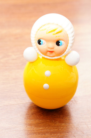 A vertical closeup shot of a plastic doll on a wooden surfaceの写真素材