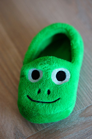 A vertical shot of a soft green slipper with a face on it for kidsの写真素材