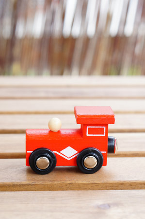 A vertical closeup shot of a wooden red toy train on a wooden tableの写真素材