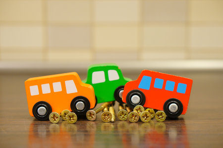 A closeup shot of wooden toy cars on golden screws on a wooden surface with a blurry backgroundの写真素材
