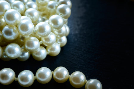 A closeup of pearls on a black surface under the lightsの写真素材