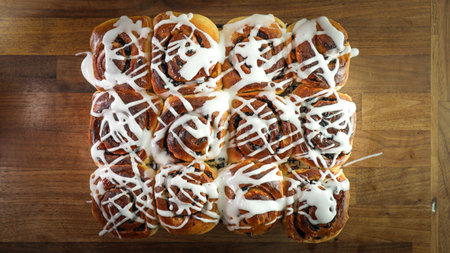 A closeup shot of glazed cinnamon buns on a wooden tableの写真素材