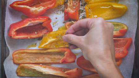 A top view shot of a male seasoning yellow and red sliced peppersの写真素材