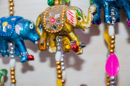 A closeup shot of hanging metallic elephant ornaments with bells on its foot with a white backgroundの写真素材