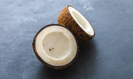 An overhead closeup shot of cut coconuts on a grey background - perfect for wallpaper