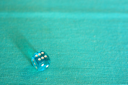 Blue plastic dice with 6 dots laying on a material background in soft focus. Horizontal high angle view.の写真素材