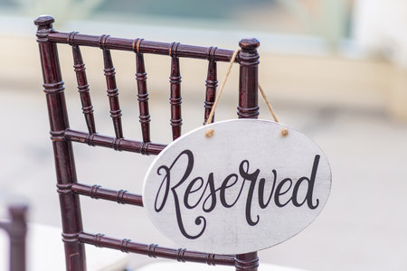 A closeup shot of a reserved sign hanging on a chair at a wedding ceremonyの写真素材