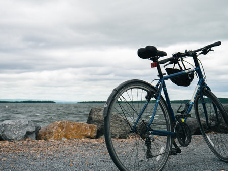 A blue mountain bike parked on a sea shore under a cloudy skyのeditorial素材