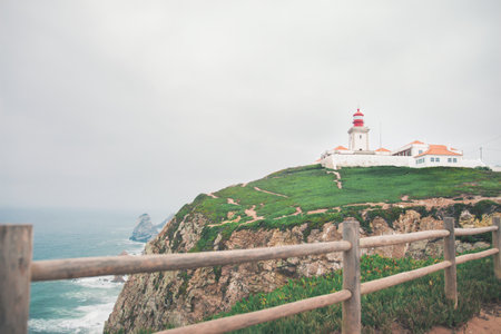 A beautiful view of Cabo da Roca Lighthouse on the cliff in Colares, Portugal with a cloudy gray sky in the backgroundのeditorial素材