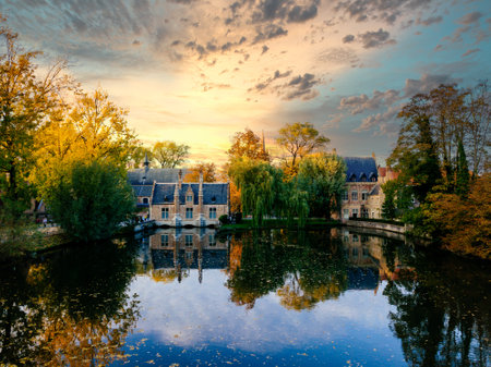 Lake Minnewater in Bruges - Belgium at Sunset with lovely tree reflexes in the water and beautiful colourful skiesのeditorial素材