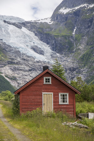 Abandoned village with different colored wooden houses in an idyllic location, between mountains, glacier in the background, abundant green vegetationのeditorial素材