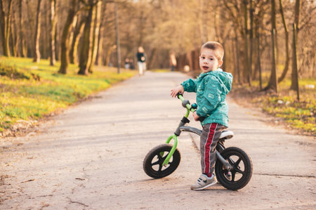 POZNAN, POLAND - Mar 18, 2020: Young two years old Polish Caucasian boy sitting on a running bike on a footpath at a park.のeditorial素材