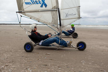 IJMUIDEN, NETHERLANDS - Jun 17, 2017: People riding a blokarts at the beach under a cloudy sky with the sea in the backgroundのeditorial素材