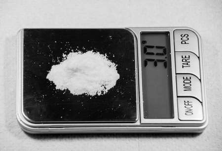 A closeup of a white powder weighed on a scale perfect for heroin and cocaine, drug conceptの写真素材