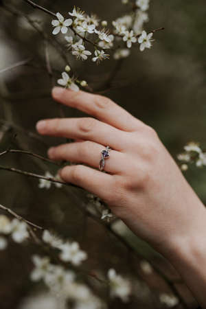 A shot of a beautiful silver ring with a purple diamond on a soft female hand