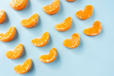 An overhead shot of mandarin slices placed on a light blue backgroundの写真素材