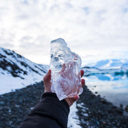A closeup of a person holding ice in Iceland with a blurry backgroundの写真素材