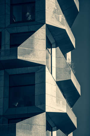 A vertical grayscale shot of a modern building covered fully with glass and stoneの写真素材