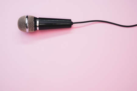 A closeup shot of a microphone with a wire isolated on a pink background with a shadowの写真素材